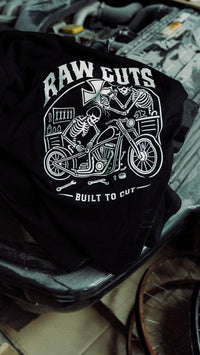 Camiseta RAW CUTS sobre el motor de un coche en el taller