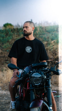 Modelo con la camiseta RAW CUTS en una moto de motocross al atardecer